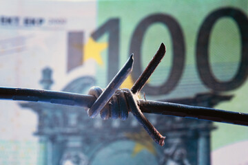 Economic warfare, sanctions and embargo busting concept. Close up barbed wire against money of...