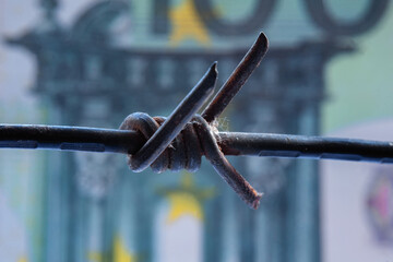 Economic warfare, sanctions and embargo busting concept. Close up dirty barbed wire against money...