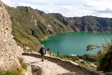 Lake Quilotoa in caldera of eponymous volcano.  Hiking patch and tourist on the way down to the lake. Cotopaxi province, Ecuador