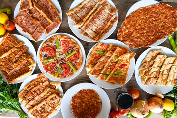 Traditional Turkish cuisine. Pizza, pita, pidesi, sucuk, hummus, kebab. Many dishes on the table. Serving dishes in restaurant. Background image. Top view, flat lay