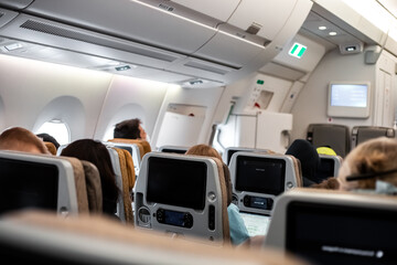 The passenger cabin of the aircraft with people in the chairs. Comfortable flight conditions on an...