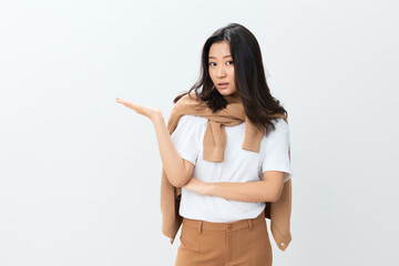 Excited pensive lovely Korean young female in beige warm sweater point hands aside at copy space posing isolated on white studio background. The best offer for ad. Autumn style concept. Seasonal Sale