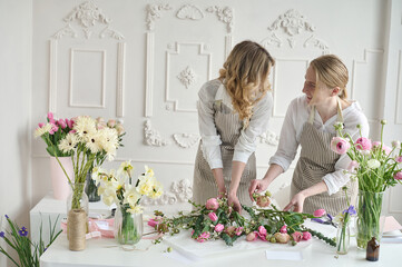 Teamwork. Two young beautiful florists create a bouquet