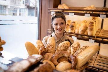 Portrait of beautiful bakery seller working with fresh pastry and bread.