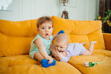 two babies playing on a yellow sofa