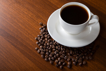 Coffee beans with a cup of coffee on wooden background	