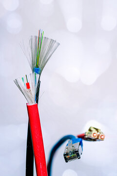 Cut fiber optic cable with fiber optic connectors and a RJ45 patch cord on a white background.