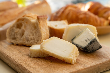 Sunny morning in Provence, breakfast with fresh baked croissants, baquett bread, crottin goat cheese and view on fisherman's boats in harbour of Cassis, Provence, France