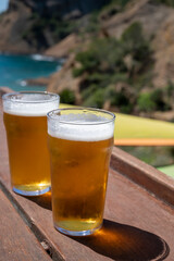 Two glasses of fresh cold lager beer served outdoor in snack bar with view on Calanque de Figuerolles in La Ciotat, Provence, France