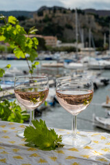 Rose wine in glasses served on outdoor terrace with view on old fisherman's harbour with colourful boats in Cassis, Provence, France