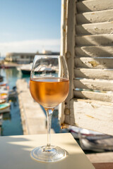 Cold rose wine in glass served on outdoor terrace in sunlights with view on old fisherman's harbour...