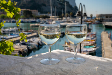 Two glasses of white wine from Cassis region served on outdoor terrace with view on old fisherman's...