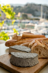 French goat cheese selles-sur-cher and fresh croissants served with view on boats in harbor of...