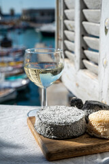 French goat cheeses crottin and selles-sur-cher served with view on boats in harbor of Cassis, Provence, France with glass of dry white wine