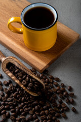Yellow cup of coffee with coffee beans on wooden background	