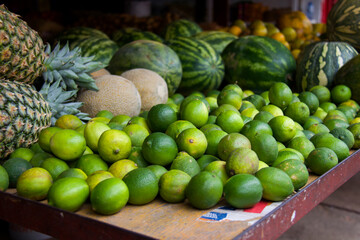 Lemons, melons, pineapple and watermelons in the background, in a market with daylight