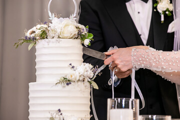 Married couple's cutting a wedding cake hands close up