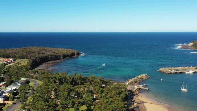 Pacific ocean to Ulladulla town with fishing marina harbour &ndash; aerial pano 4k.
