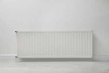 Modern radiator on white wall indoors. Central heating system