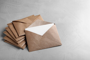 Many brown paper envelopes on light grey table. Space for text