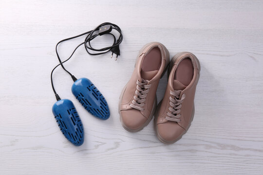 Shoes and electric dryer on white wooden background, flat lay