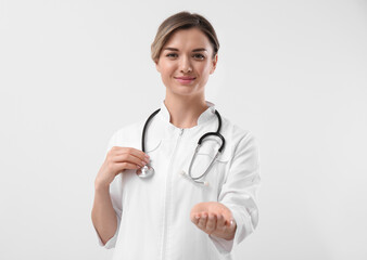 Doctor with stethoscope holding something on white background. Cardiology concept