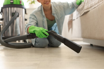 Fototapeta na wymiar Young woman vacuuming floor in bedroom, closeup