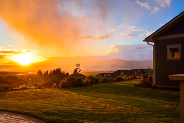 A colorful mist of rain covers the Spokane Valley as the sun reflects the sunset behind the...