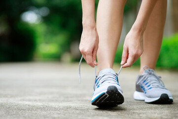 Running shoes. close up female athlete tying laces for jogging on road. Runner ties getting ready...