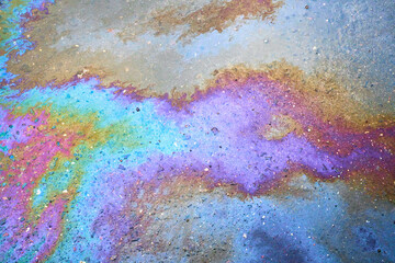 Oil stain on the asphalt, rainbow-shaped colored gasoline stains on an asphalt road as a texture or background