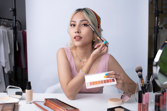 Young beautiful Asian woman and professional beauty make up artist vlogger or blogger recording makeup tutorial to share on website or social media. Business online influencer on social media concept.