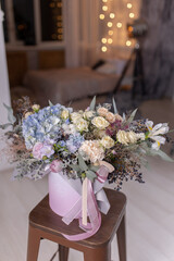 Flower arrangement in a round box with blue hydrangea, peonies and roses