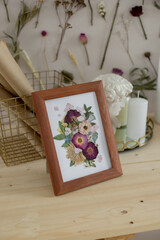 Fototapeta na wymiar Picture of dried flowers in a wooden frame on the desktop in the interior