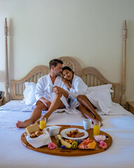 A couple man and women mid age having breakfast in bed bedroom of an apartment luxury hotel condo...