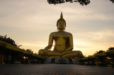 Obraz premium The famous public landmark shiny yellow golden big buddha portrait statue with blue sky background Thailand.