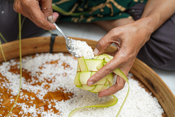 The process of making ketupat is a traditional food during Eid. Put the rice in the ketupat container.