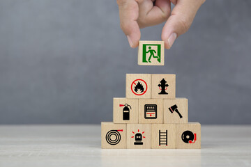 Hand choose wooden block stack with door exit sing or fire escape and fire prevent icon with fire extinguisher and emergency protection symbol for safety and rescue in the building.