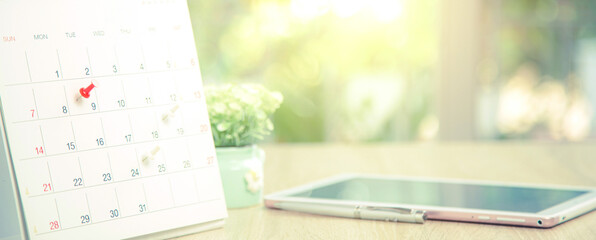 Close up pin on business desk calendar with office equipment concept of event planner or personal organization reminder and schedule or planning.