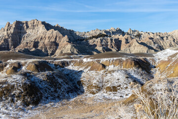A light snow sits on the grass of the natural landscape of Badlands National Park in South Dakota