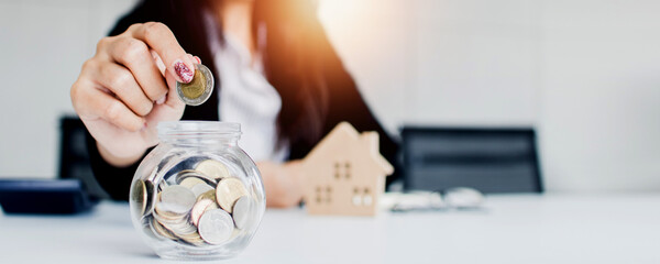 close up hand of woman save and put money coins in bottle glass, saving finances and budget bank concept