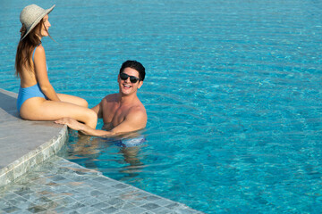 happy young couple by the pool. couple are relaxing at swimming pool party. Summer vacation holiday trip concept