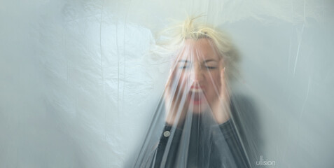 panorama banner of blurred portrait of a young blonde woman behind transparent plastic foil as a...