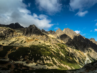 Panoramic view of the autumn mountains. Green and yellow  granite mountains against a blue sky with clouds
