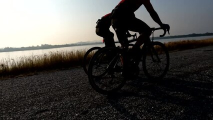 Men riding bicycle wearing bicycle helmet, cycling sunglasses on road exercising summer outdoor over sunrise in the morning, 4K. Concept of Bike, Bicycle, Cycling, Sport, Outdoor, Healthy Care