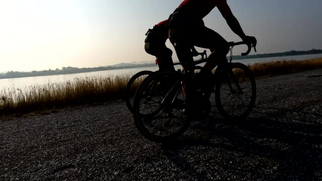 Men riding bicycle wearing bicycle helmet, cycling sunglasses on road exercising summer outdoor over sunrise in the morning, 4K. Concept of Bike, Bicycle, Cycling, Sport, Outdoor, Healthy Care