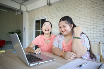 down syndrome teenage girl and her teacher studying how to use laptop computer for education, and raised arm pose in success