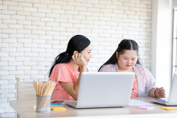 down syndrome teenage girl and her teacher using laptop computer and studying math on a table