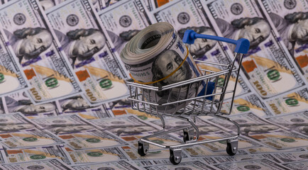 Symbolic miniature supermarket shopping cart and 100 american dollar bills