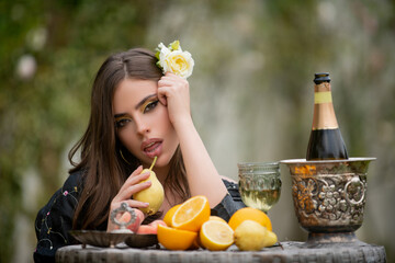 Outdoor fashion portrait sexy woman eating pear, relaxing near summer garden with tropical fruits. Beauty woman face.