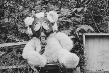 A teddy bear in a gas mask lies on the ground in the grass, gas attack, war in Ukraine, chemical...